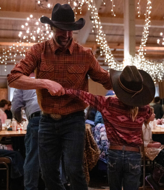 A father and young son dance together during a Western BBQ at Steamboat Resort's Thunderhead Lodge.